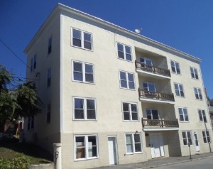 a 4 floor apartment building with beige walls, white doors, and square windows