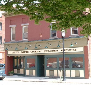 a red brick storefront with green bordered first floor windows, green lamps, and horizontal sign reading: Greater Gardner Community Development Corporation