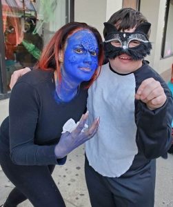 a woman dressed as Mystique and a young boy dressed as a black cat pose for a Halloween picture