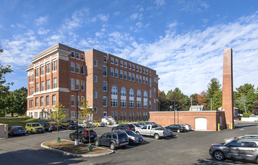 a large brick building with a parking lot and a smaller brick building in front