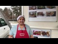 a woman in a red apron and headband stands in front of a wall with photos