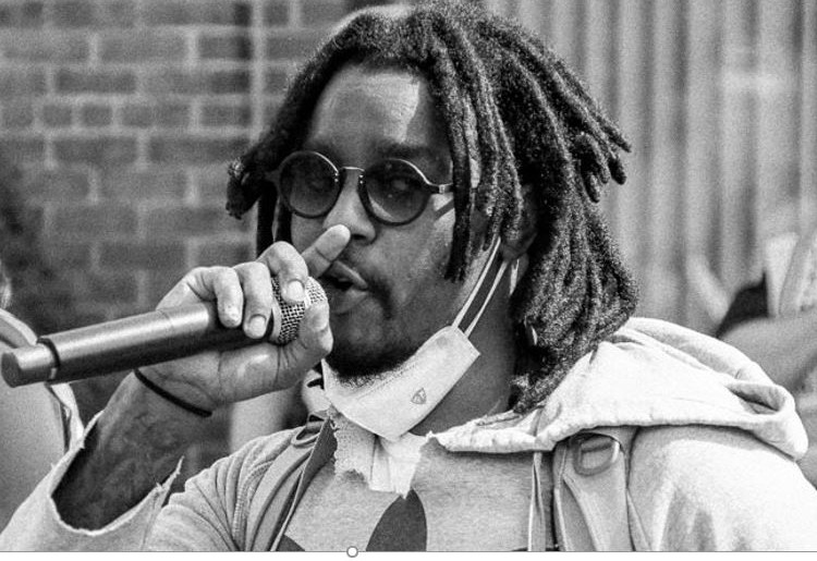 a black and white photo of a man speaking into a handheld microphone